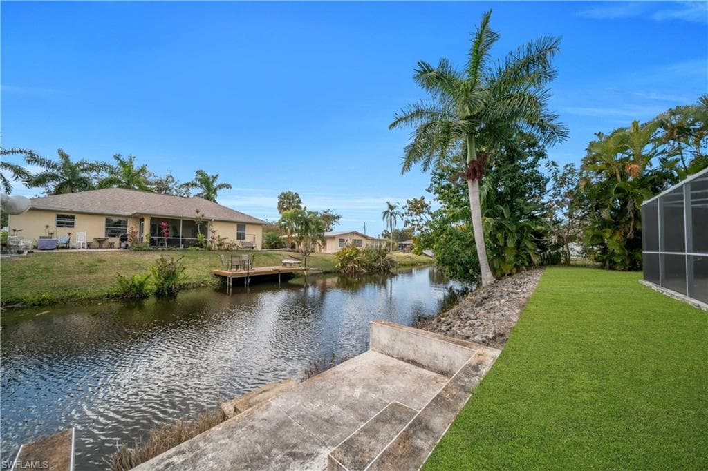 Dock area with a water view, a lanai, a yard, and a sunroom