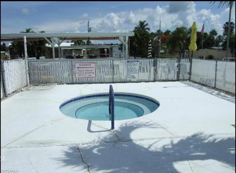 View of swimming pool with a hot tub
