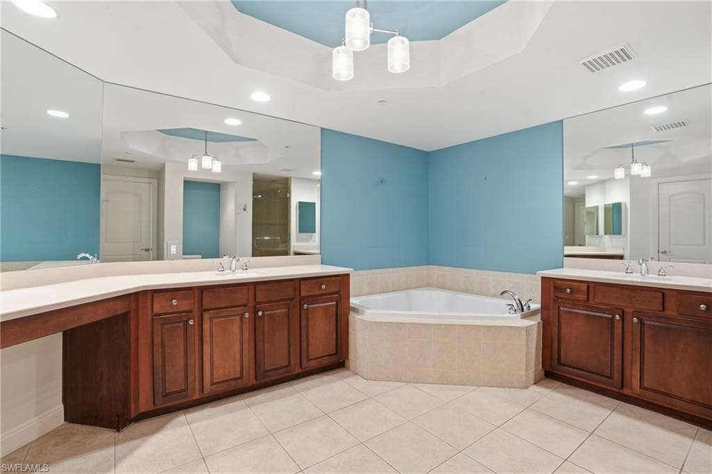 Primary bathroom with a raised ceiling, a shower stall, recessed lighting, a bath, and two vanities