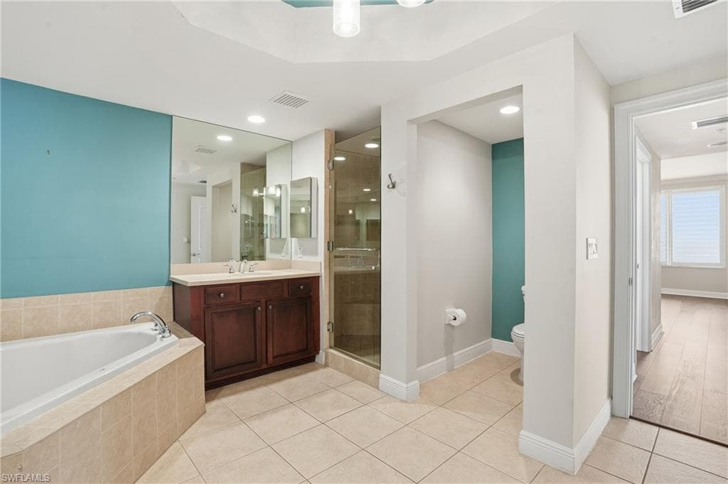 Primary Bathroom featuring a shower stall, light tile patterned flooring, a bath, vanity, and recessed lighting