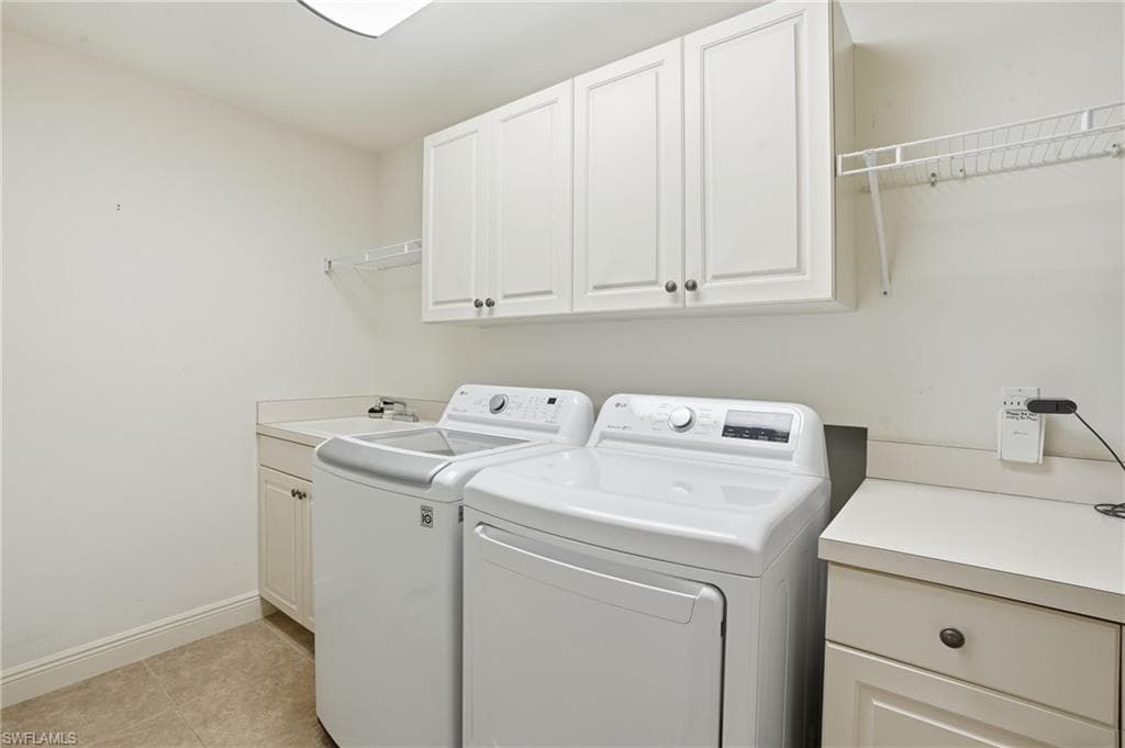Laundry room featuring separate washer and dryer, cabinet space, and light tile patterned flooring