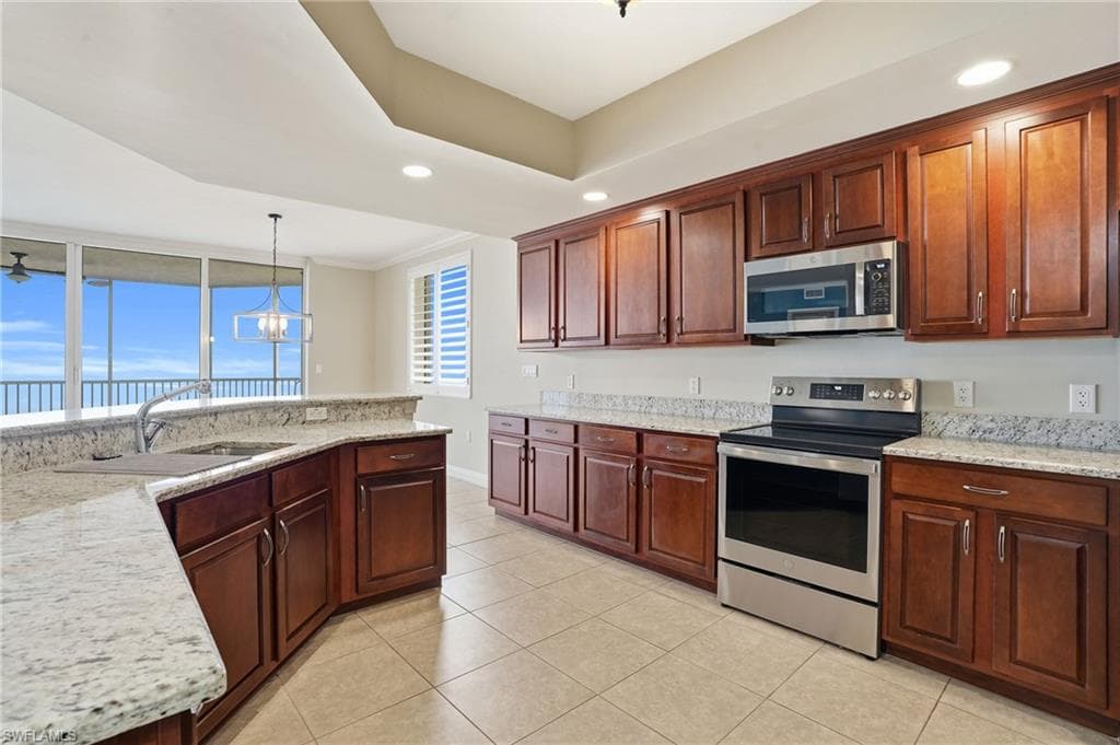 Kitchen with stainless steel appliances, granite countertops, light tile flooring, a chandelier, and crown molding