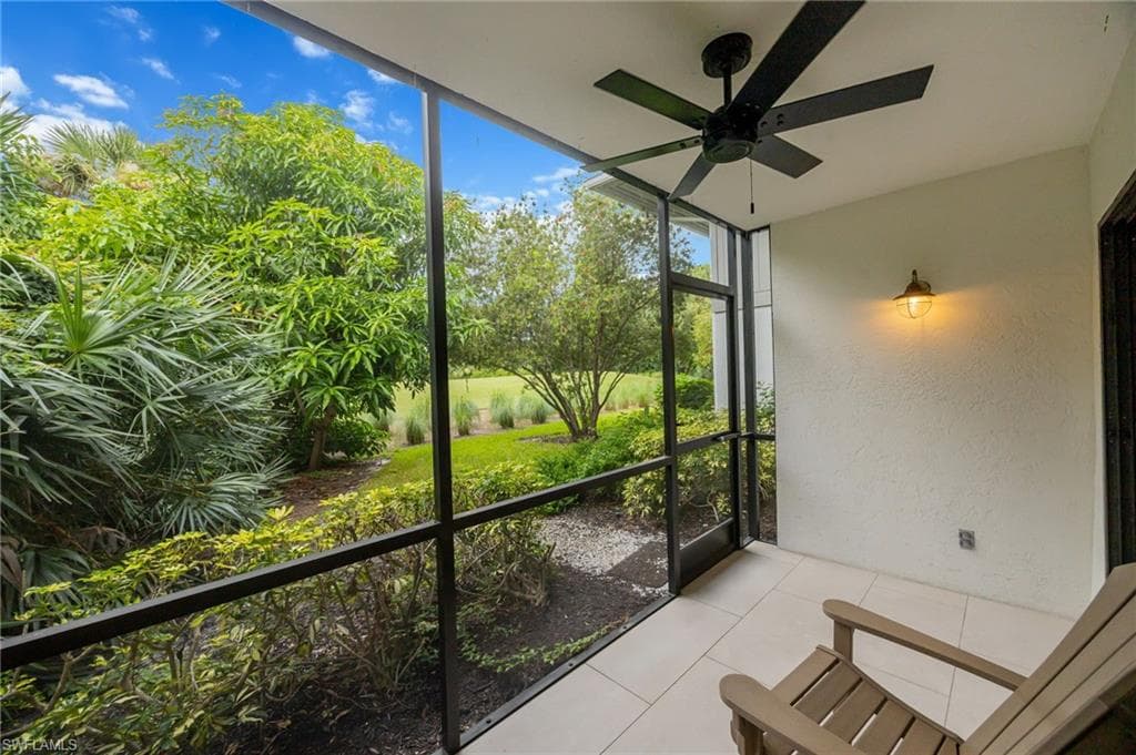 Screened patio featuring a ceiling fan, wall-mounted light fixture, and tile flooring