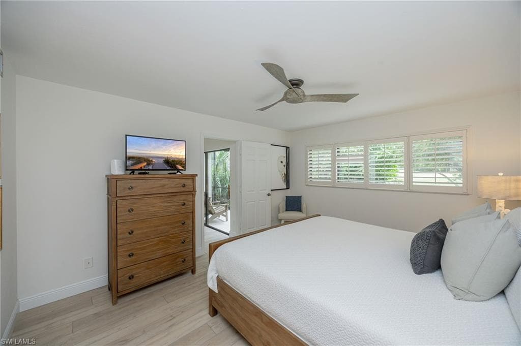 Wood-finish flooring, ceiling fan, white window shutters, and a glass-paneled door