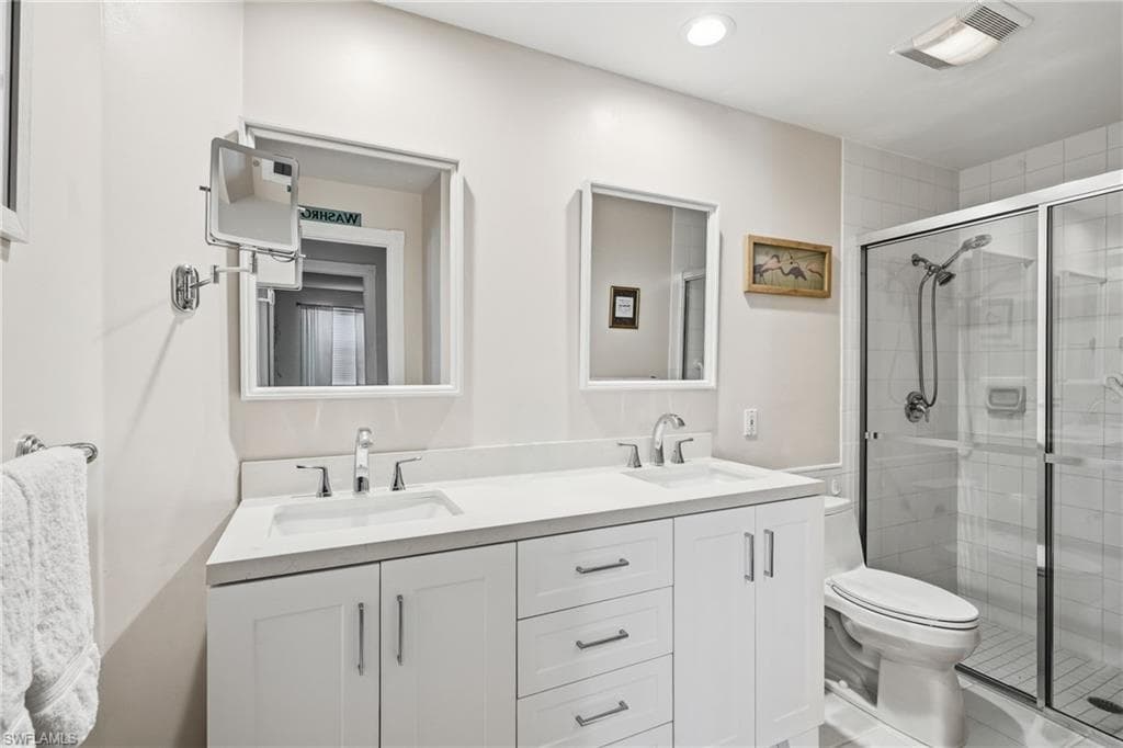 Bathroom featuring a double vanity with white cabinetry, integrated sinks, and quartz countertops