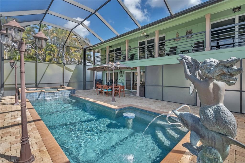 Integrated pool / hot tub featuring a sunroom, outdoor dining area, a patio area, and glass enclosure
