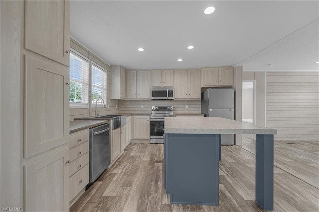 Dual tone kitchen with two tone cabinetry, stainless steel appliances, light wood finished floors, recessed lighting, and light countertops