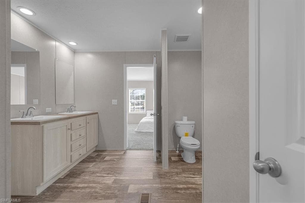 Bathroom featuring light wood-style floors, connected bathroom, double vanity, and recessed lighting
