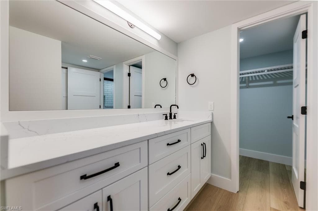Bathroom featuring a walk in closet, vanity, light wood-type flooring, and recessed lighting