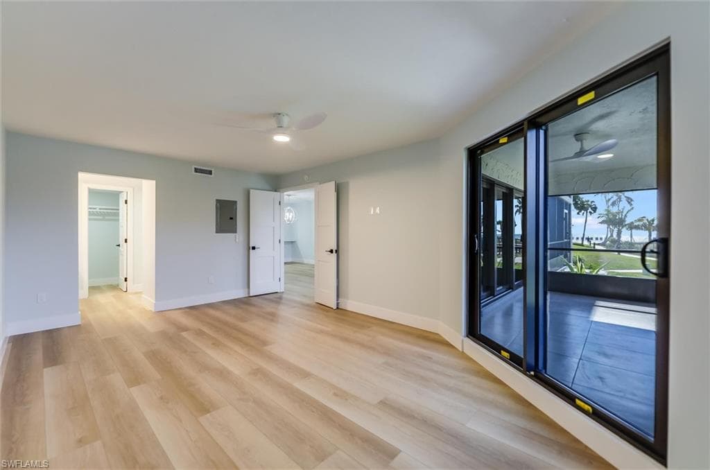 Unfurnished room featuring a ceiling fan, light wood-style flooring, and electric panel