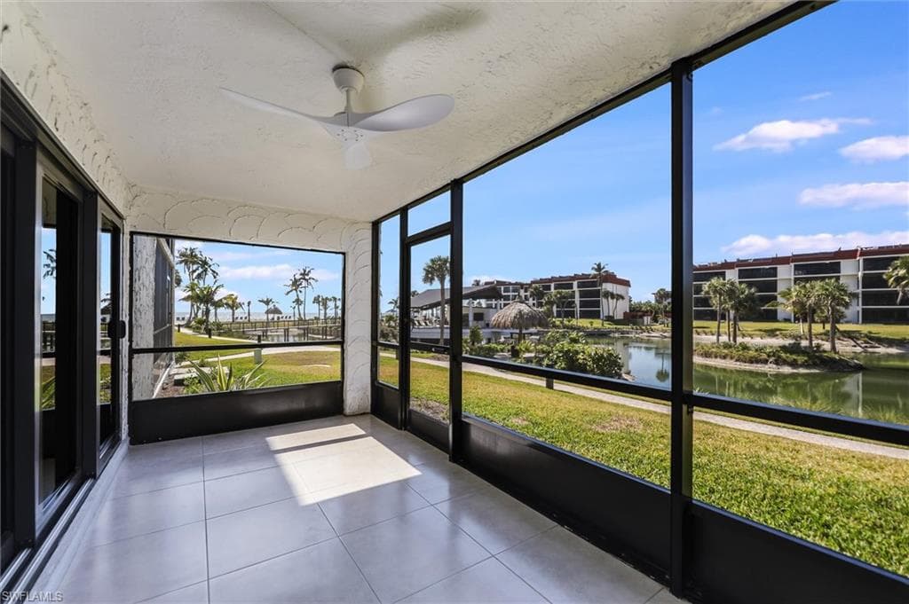 Unfurnished sunroom featuring a ceiling fan and a water view