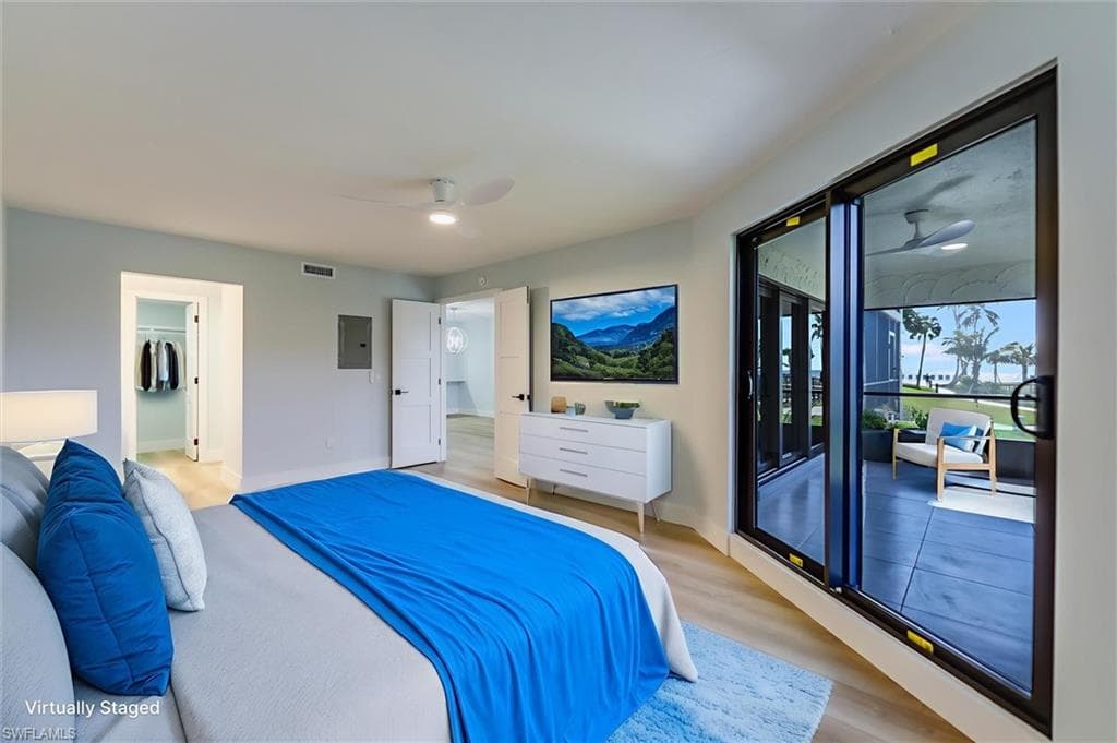 Bedroom featuring access to outside, light wood-style floors, ceiling fan, a walk in closet, and electric panel