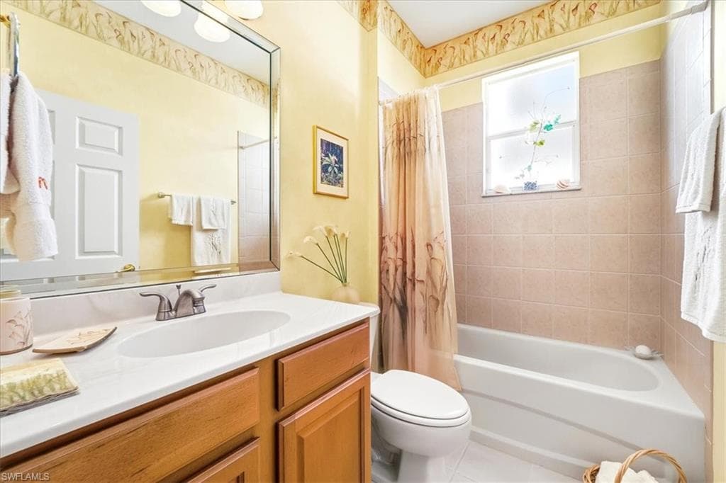 Bathroom featuring vanity, shower / tub combo with curtain, and tile patterned flooring