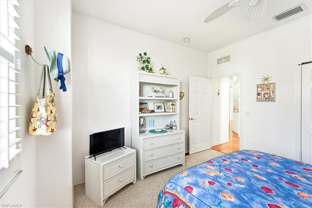 Bedroom with multiple windows, light colored carpet, and a ceiling fan