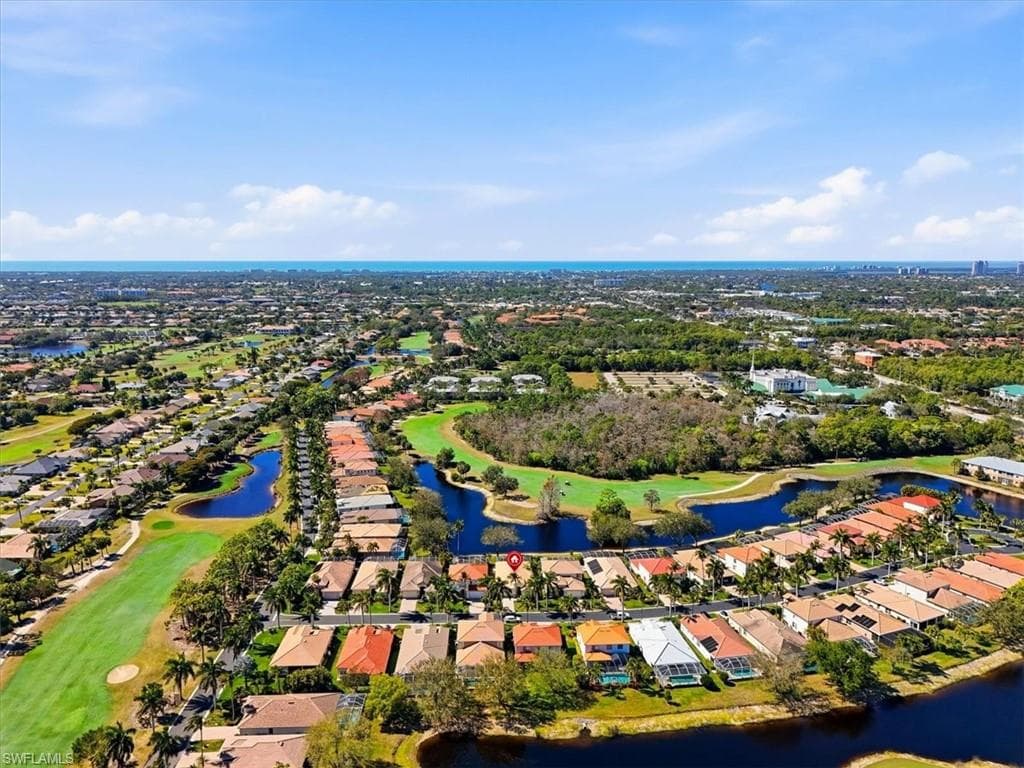 Aerial perspective of suburban area featuring a nearby body of water and a golf course