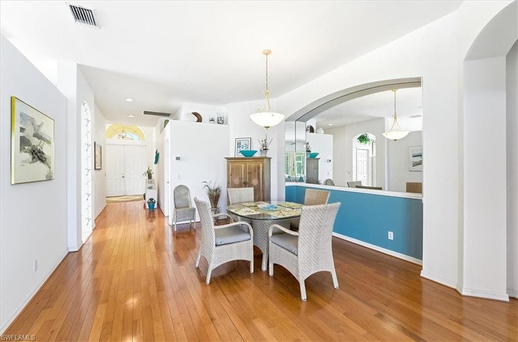 Dining room with hardwood / wood-style floors and arched walkways