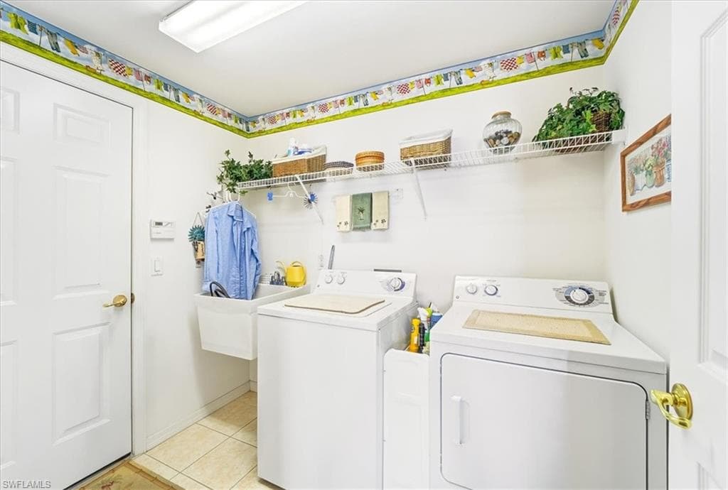 Laundry area with washing machine and clothes dryer and light tile patterned flooring
