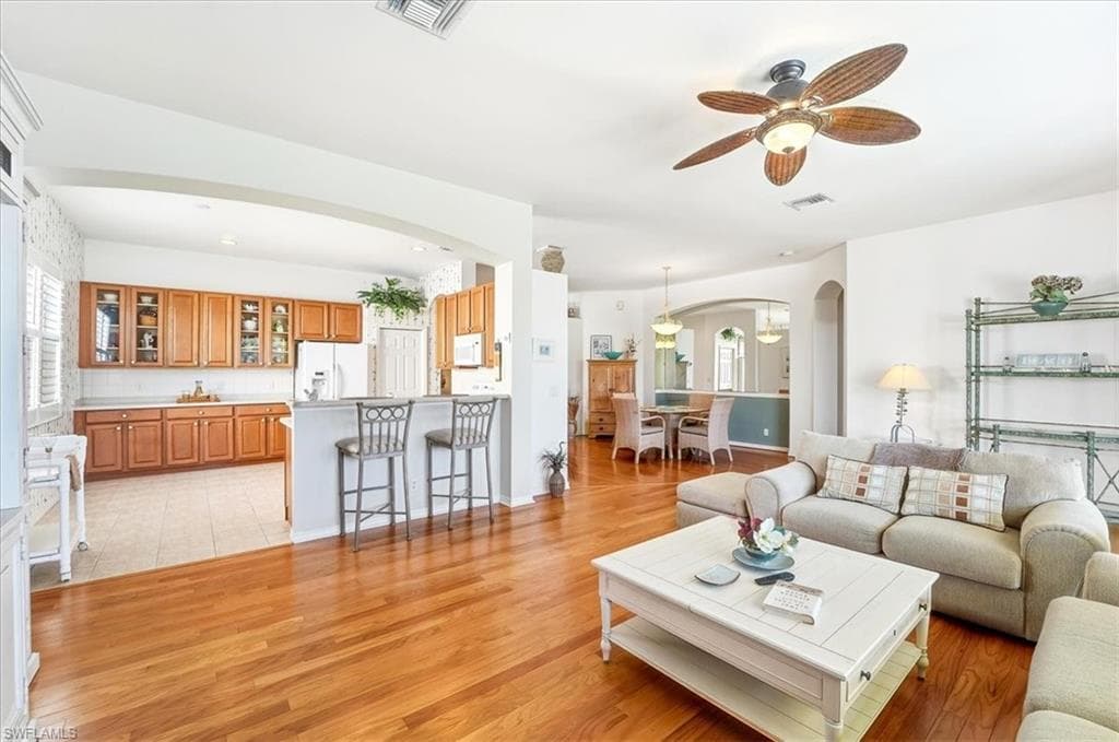 Living area featuring arched walkways, light wood-style floors, a ceiling fan, and recessed lighting