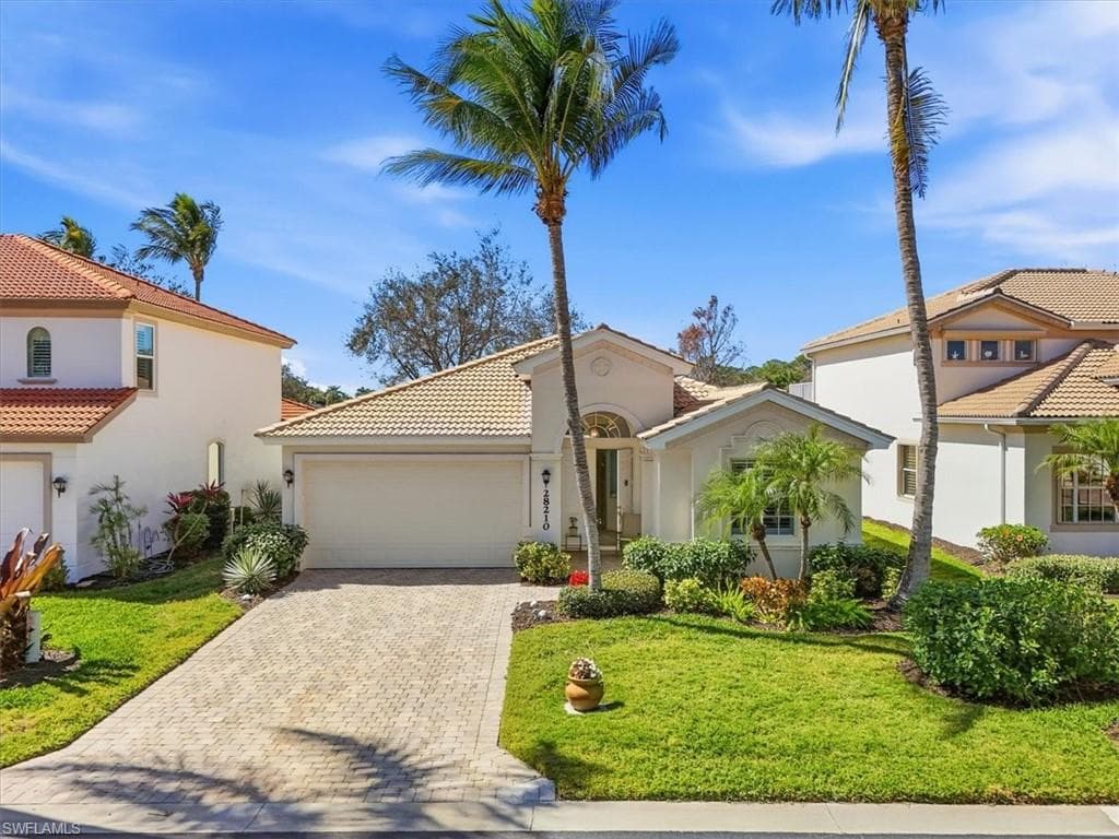 Mediterranean / spanish-style house with an attached garage, stucco siding, a front yard, decorative driveway, and a tile roof