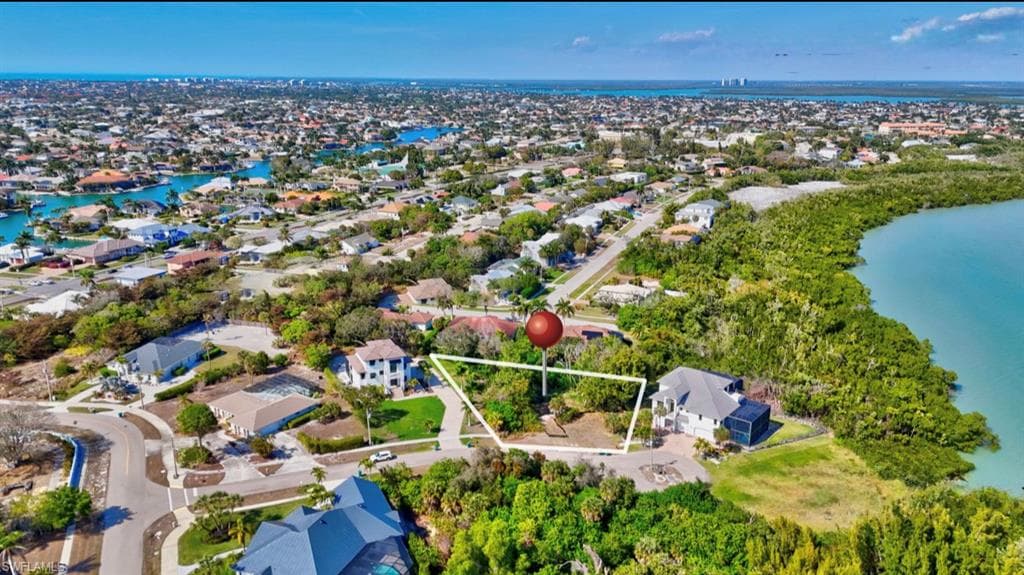 Aerial perspective of suburban area featuring a large body of water and property parcel outlined