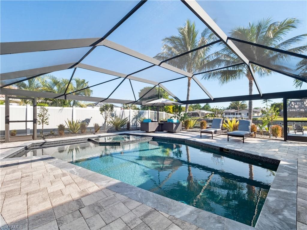 Combined pool / hot tub with a sunroom, a lanai, a patio, and a fenced backyard