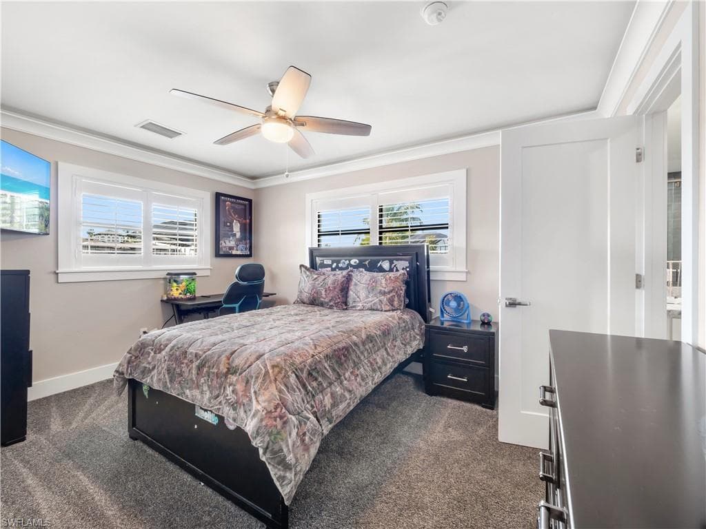 Bedroom featuring dark carpet, crown molding, and a ceiling fan