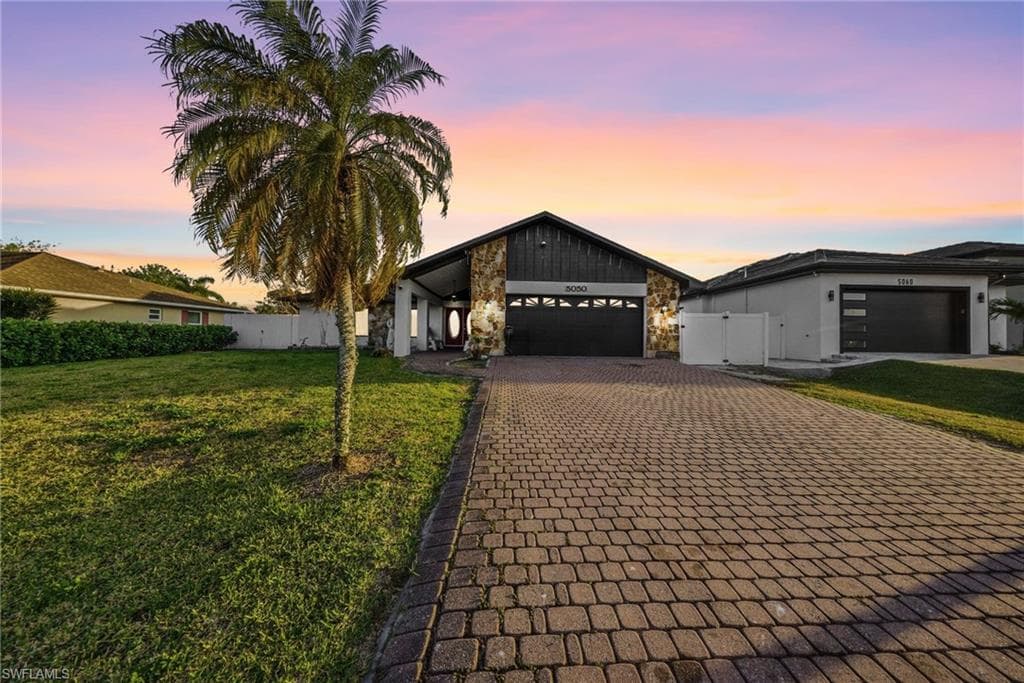 View of front of house with a garage, decorative driveway, and stone siding