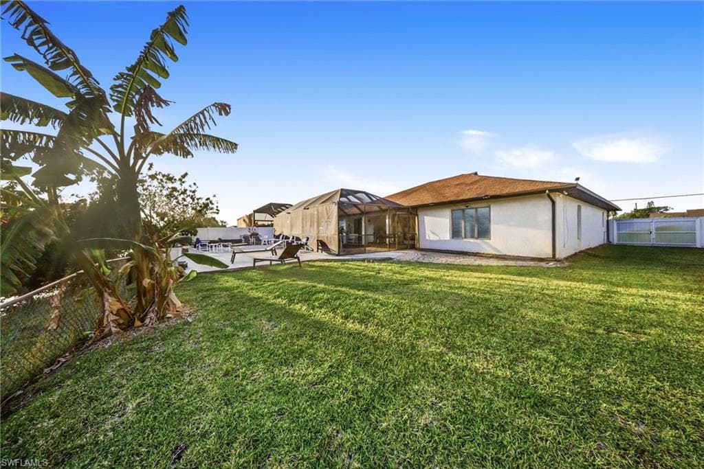Back of house with a lanai, a patio, a fenced backyard, and stucco siding