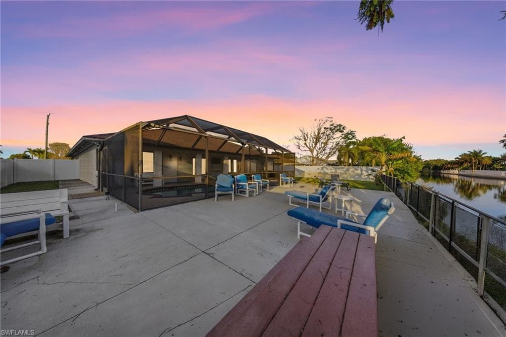 Dock area featuring a fenced backyard, a patio area, glass enclosure, a water view, and a sunroom