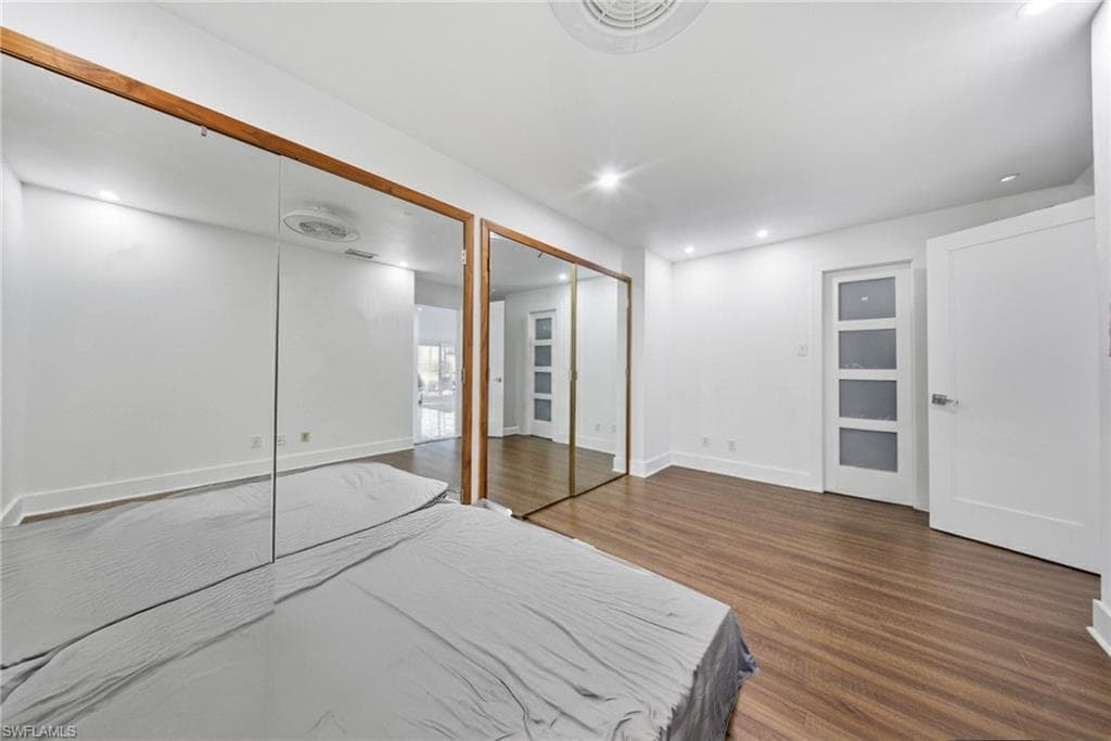 Bedroom with multiple closets, dark wood finished floors, and recessed lighting