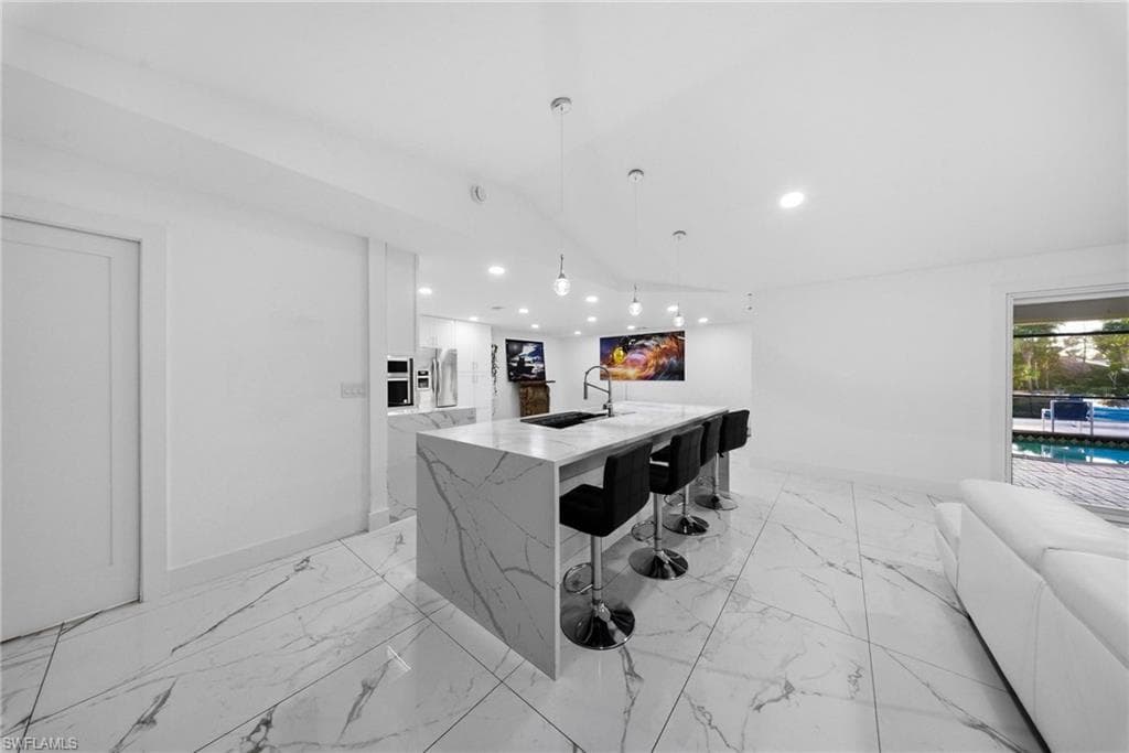 Bar area featuring modern cabinets, white cabinetry, pendant lighting, light stone countertops, and stainless steel refrigerator with ice dispenser