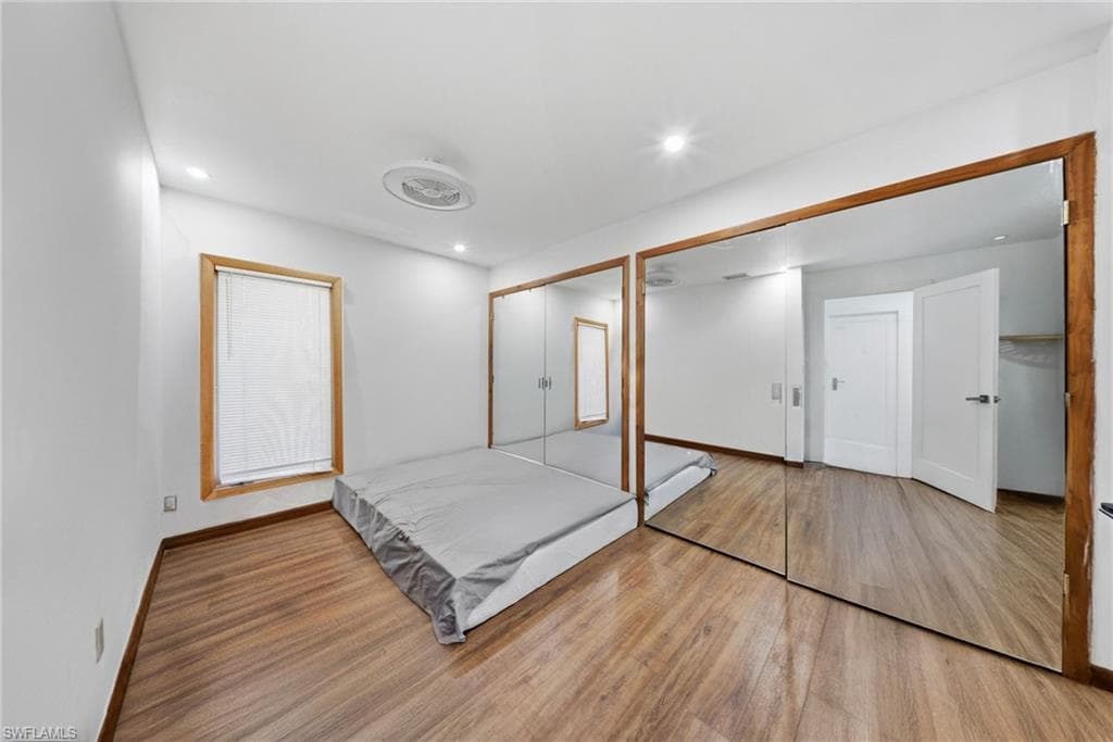 Unfurnished bedroom with wood finished floors, two closets, and recessed lighting