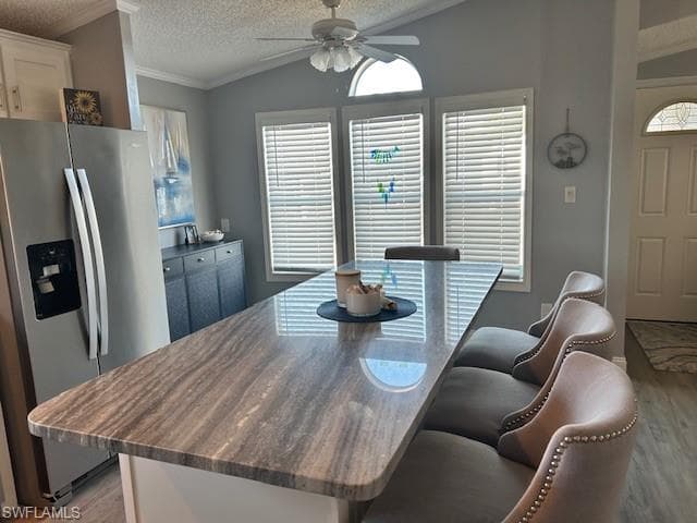 Dining area with light wood-style floors, ceiling fan, crown molding, and healthy amount of natural light