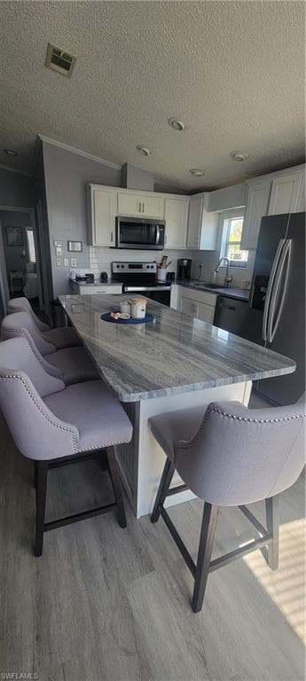 Kitchen featuring dark stone counters, a breakfast bar area, stove, white cabinetry, and a textured ceiling