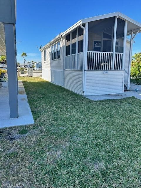 View of side of home with a sunroom and a lawn