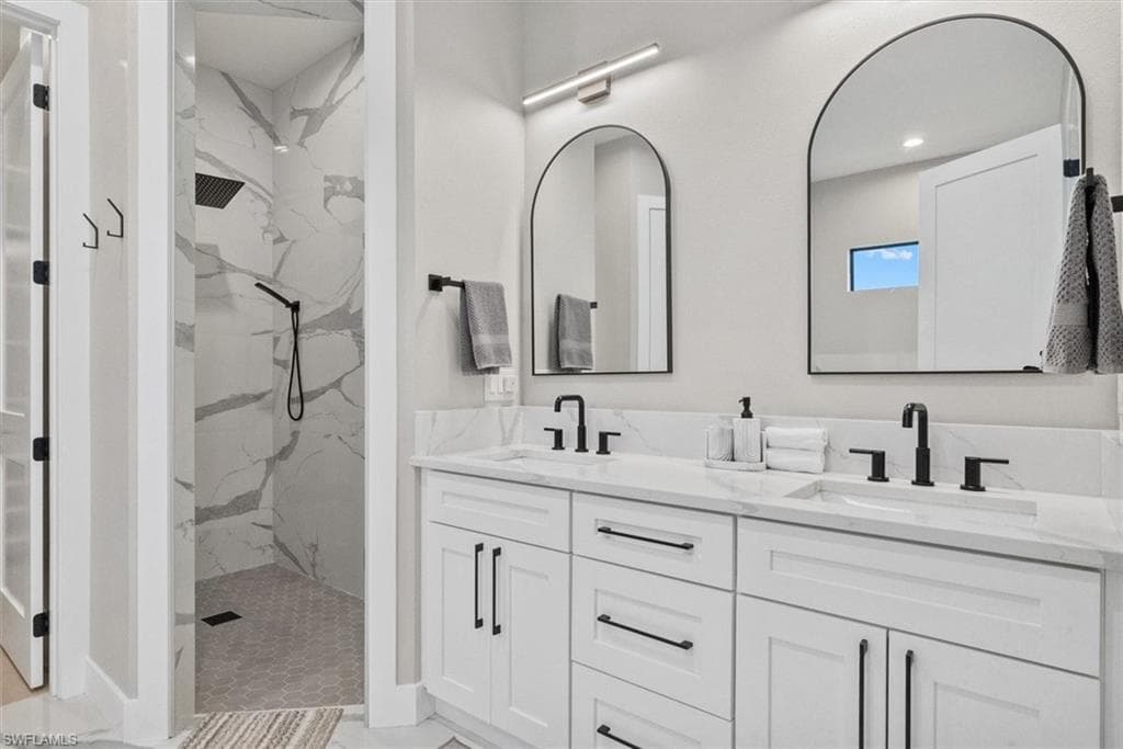 Full bath with double vanity, a marble finish shower, and recessed lighting