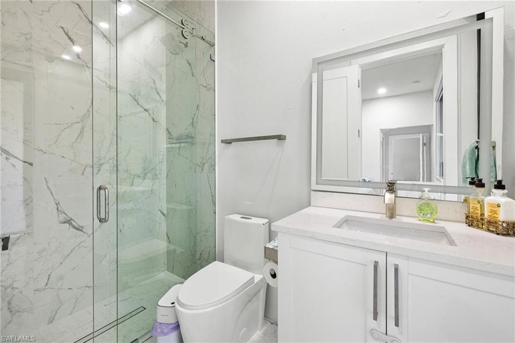 Bathroom featuring vanity and a marble finish shower