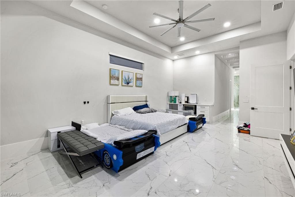 Bedroom with a raised ceiling, ceiling fan, and recessed lighting
