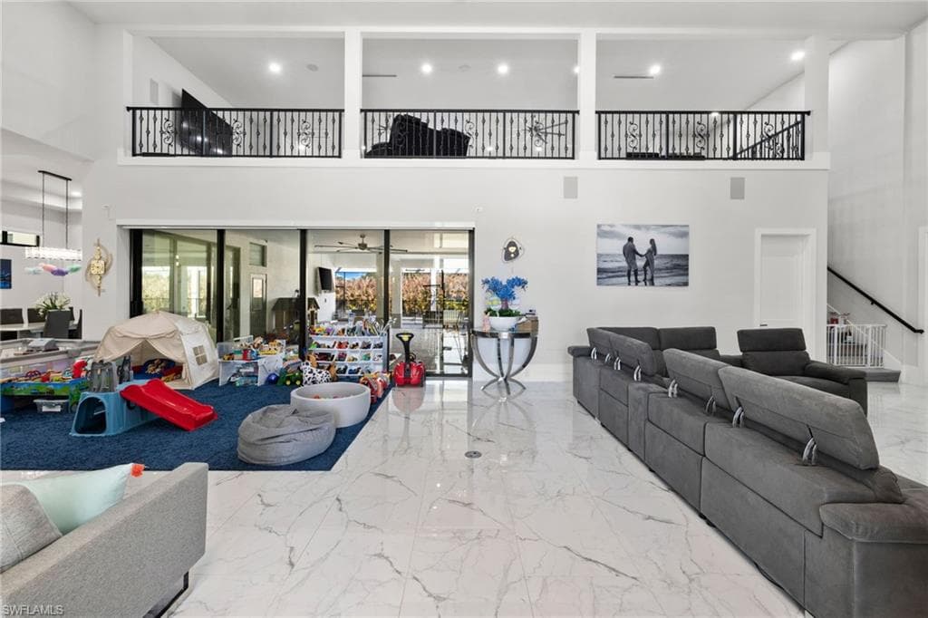 Living room featuring a high ceiling, recessed lighting, and light marble finish floors