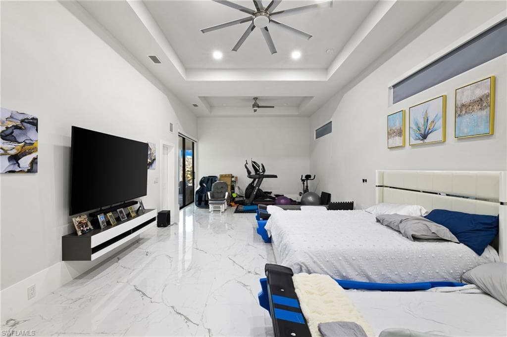 Bedroom with recessed lighting, a high tray ceiling, and light marble finish flooring