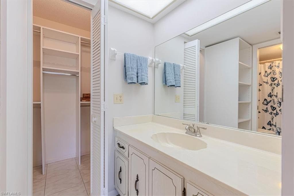 Primary Bath featuring vanity, a spacious closet, a shower, and light tile flooring