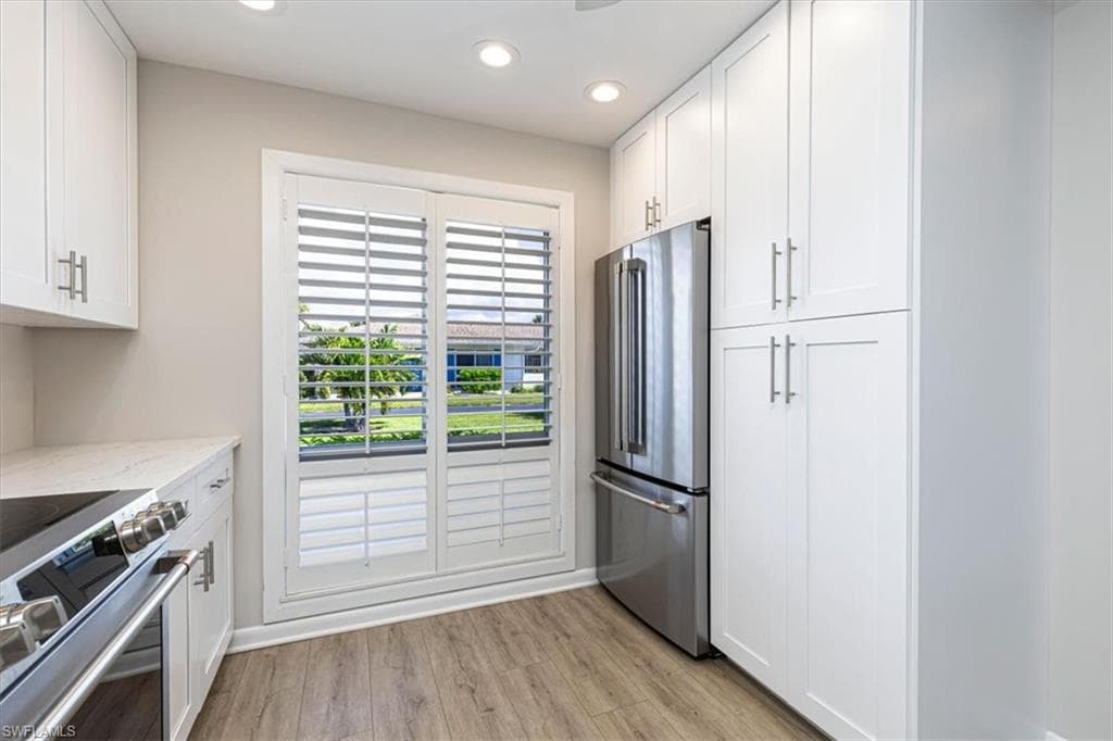 Kitchen featuring white cabinets, stainless steel appliances, light wood-style flooring, light quartz counters, and recessed lighting