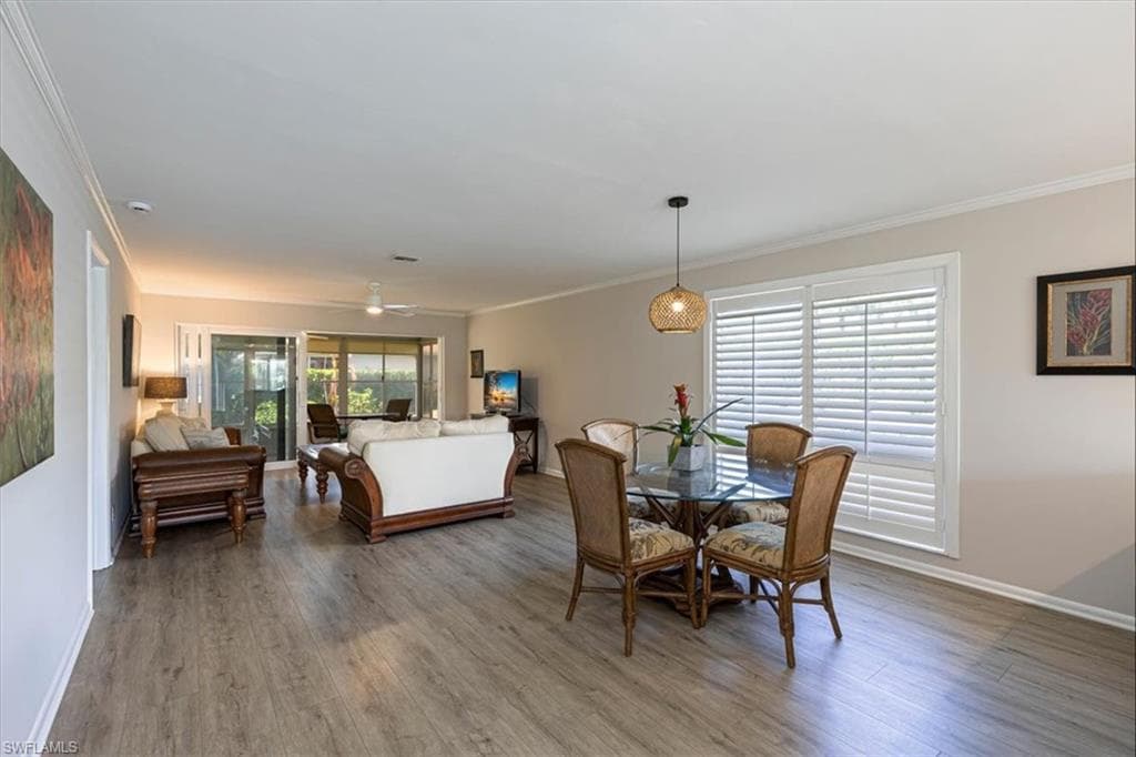 Dining area with crown molding, ceiling fan, and light wood-style floors