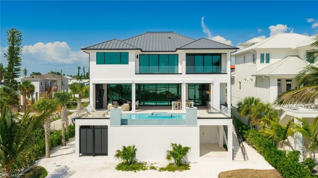 Contemporary multi-story residence featuring a dark metal roof and white exterior