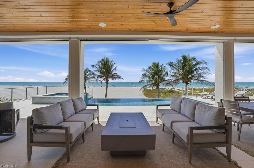 View of patio / terrace featuring outdoor lounge area, a ceiling fan, a water view, and an in-ground hot tub - Virtually Edited Image