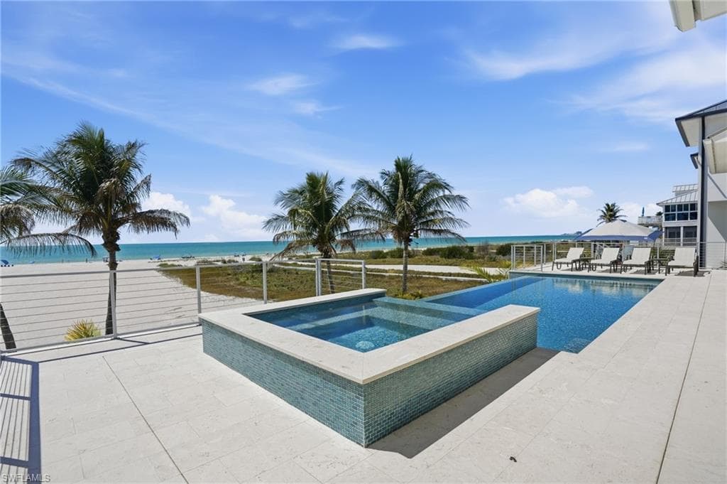 Relaxing pool / spa featuring a patio area and a water view - Virtually Edited Image
