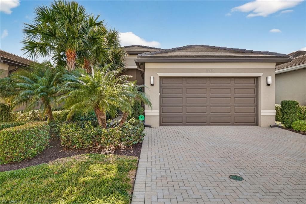 View of front of property with decorative driveway, stucco siding, and an attached garage