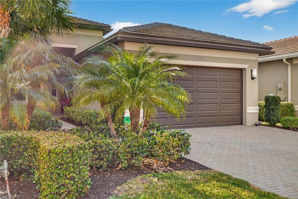 View of front of property featuring decorative driveway, stucco siding, an attached garage, and a tiled roof