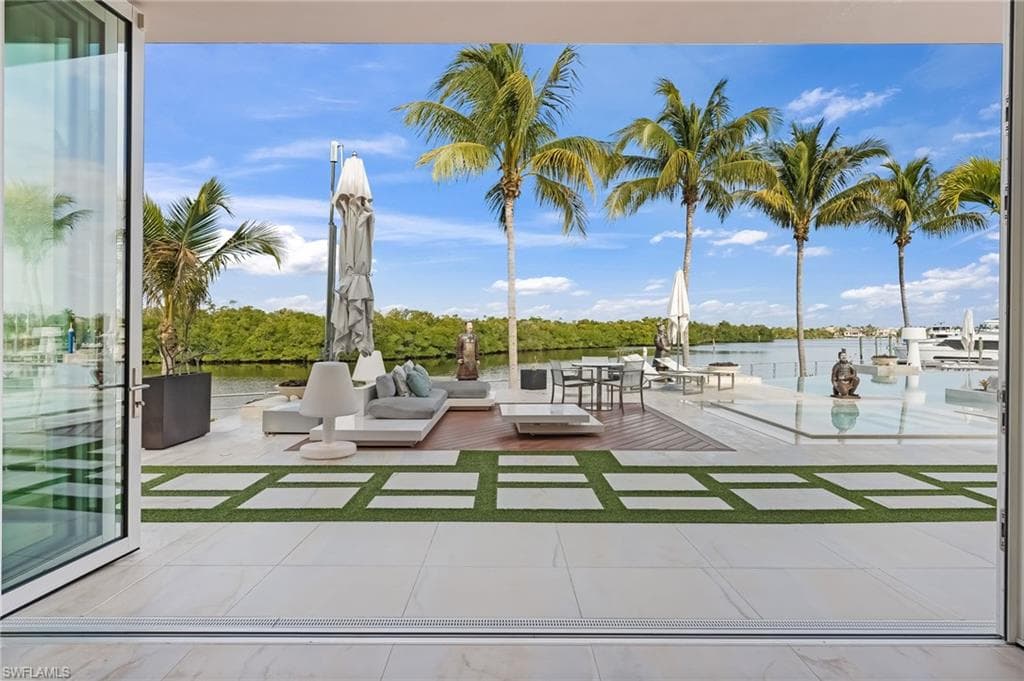 Enjoy a sense of peaceful seclusion from the primary suite, with sweeping views over the impressive pool deck, tranquil canal waters, and a scenic island on the horizon.
