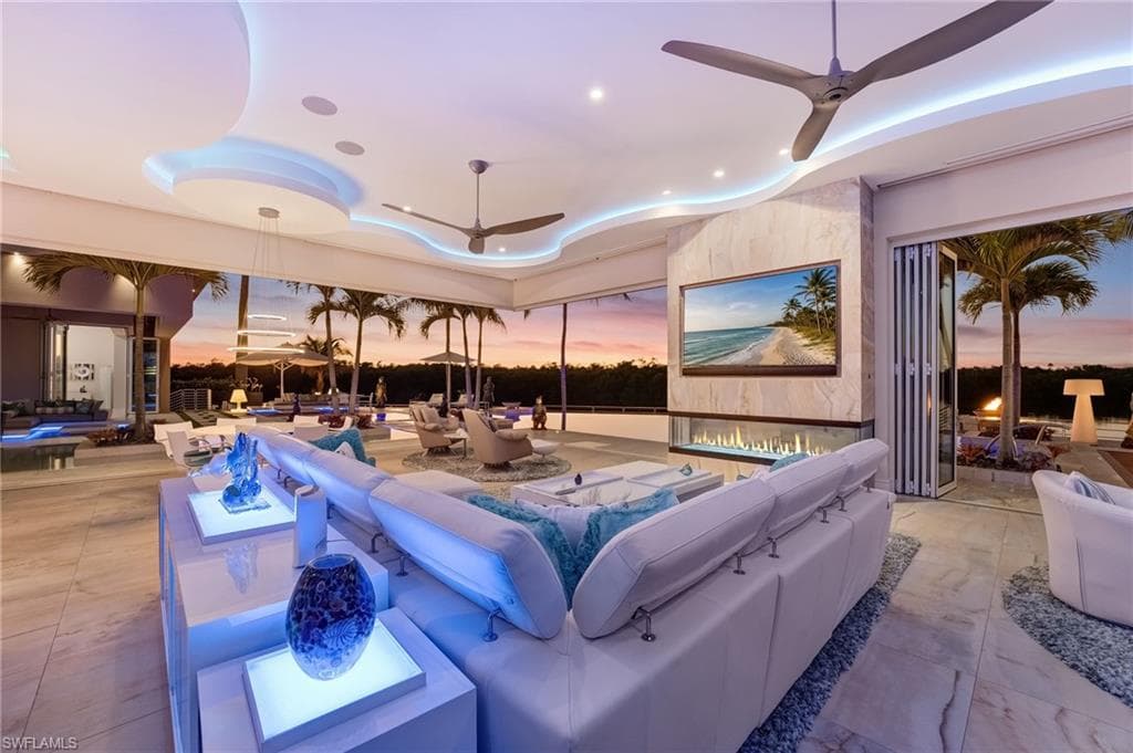 This one-of-a-kind residence is thoughtfully designed for refined, quintessential indoor-outdoor living, featuring custom cloud lighting and a contemporary fireplace that anchors the main living space. Expansive 12-foot accordion hurricane sliders seamlessly open the entire area to the outdoors, complemented by sleek, discreet A/C venting for effortless comfort and sophistication.